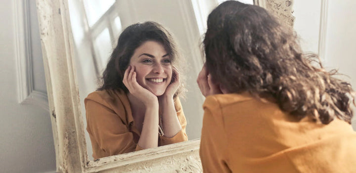 Woman smiling in the mirror after lip flip treatment in Calgary